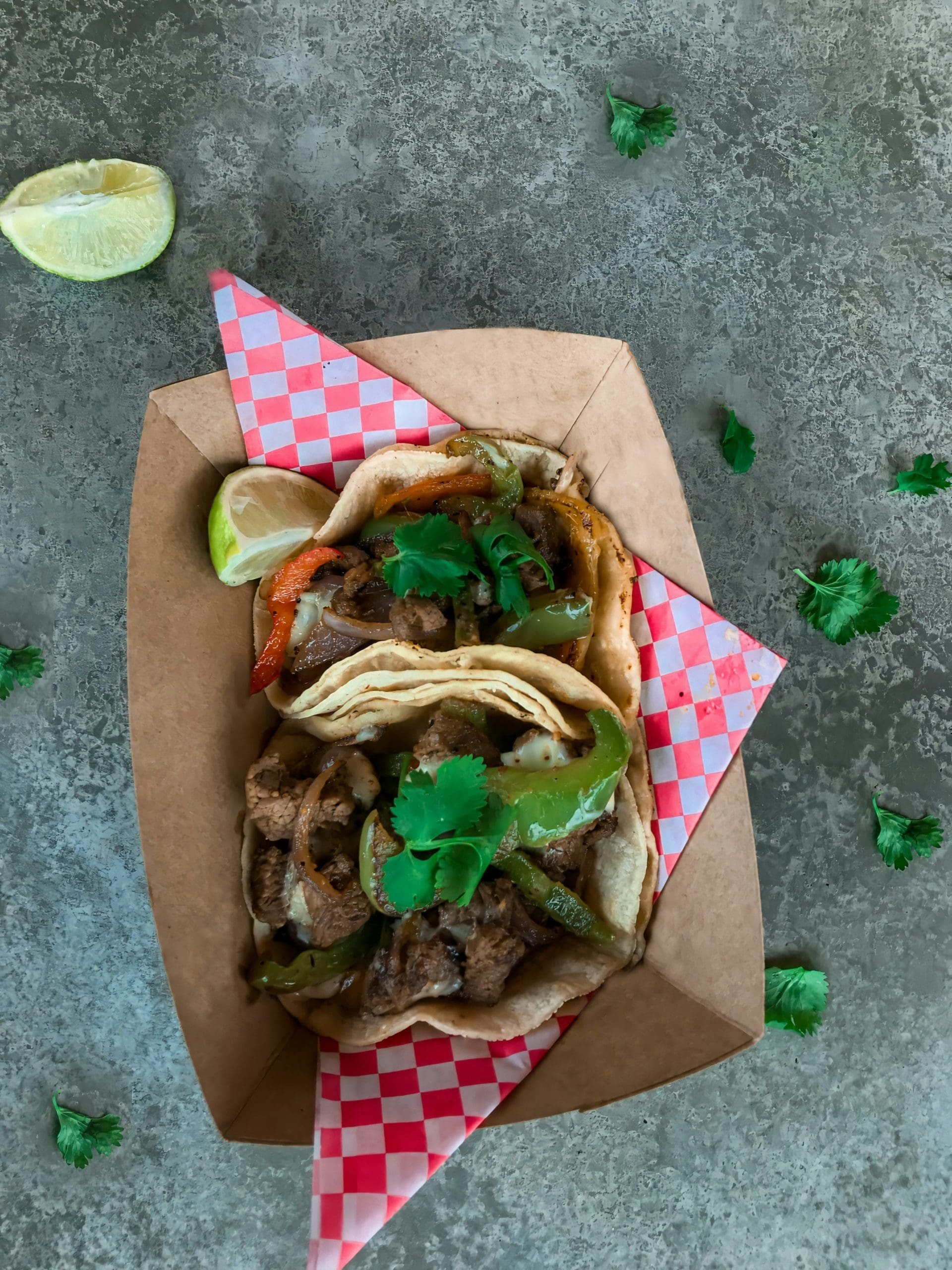 A photo of two tacos on a checkered napkin.